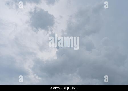 A view of an overcast sky filled with thick, textured clouds. The clouds are varying shades of gray, creating a dramatic and moody atmosphere from bel Stock Photo