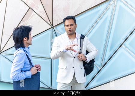 Two professional men engaged in a conversation in Melbourne, with a modern urban backdrop. The image captures the essence of business interaction and Stock Photo