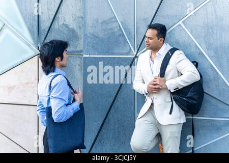 Two professional men engaged in a business conversation, set against a modern architectural backdrop in Melbourne, illustrating networking and career Stock Photo
