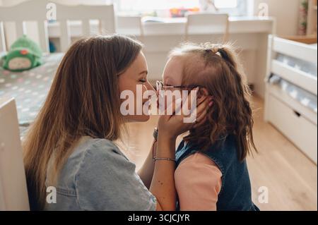 A mother and daughter with Down syndrome share a tender and loving moment, conveying warmth and affection. The intimate setting highlights their stron Stock Photo