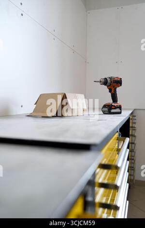 A modern workshop undergoing renovation is shown with a drill and cardboard on a workbench. The space is being prepared for a new cycling repair shop Stock Photo