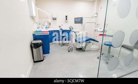 Contemporary dental office featuring a blue and white color scheme, complete with advanced dental chair, tools, and equipment, emphasizing cleanliness Stock Photo