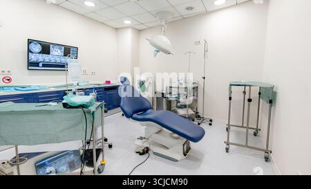 A modern dental clinic room equipped for implant procedures, featuring a reclining chair, advanced dental tools, and a clean, sterile environment for Stock Photo