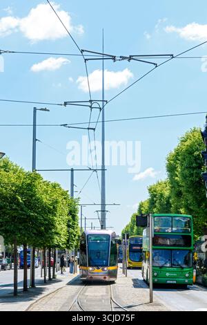 A Citadis 401 tram and a Volvo double decked tour bus on O'Connell Street, Dublin, Ireland.  The Spire in the distance. Stock Photo