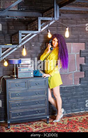 moscow, russia, 16.04.2021 Woman with purple dreadlocks using a retro rotary phone. Nostalgic communication concept in a stylish loft interior. Stock Photo