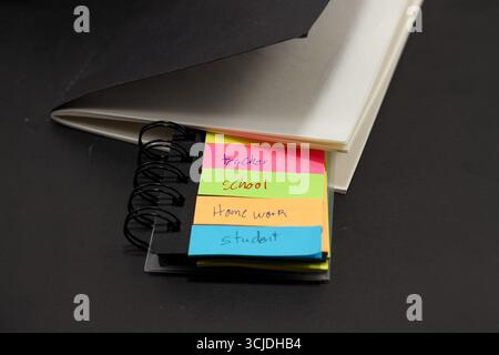 sticky notes with the words teacher, student, school, homework with a black notebook behind them Stock Photo