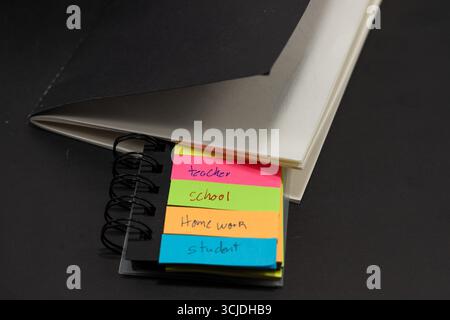 sticky notes with the words teacher, student, school, homework with a black notebook behind them Stock Photo