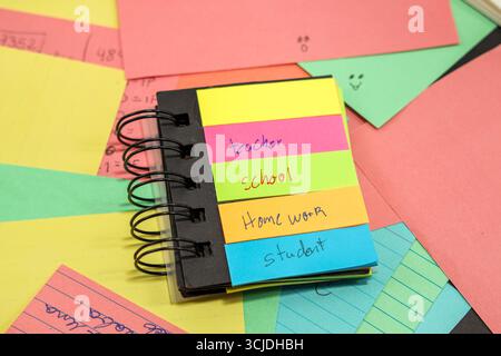 sticky notes with the words teacher, student, school, homework with more colored paper behind them Stock Photo