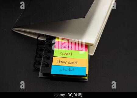 sticky notes with the words teacher, student, school, homework with a black notebook behind them Stock Photo