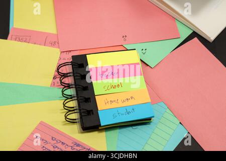 sticky notes with the words teacher, student, school, homework with more colored paper behind them Stock Photo