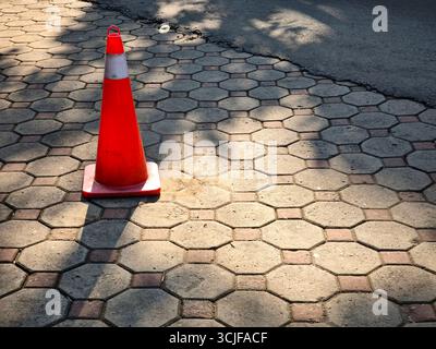 A cone sign stands on a concrete block sidewalk Stock Photo