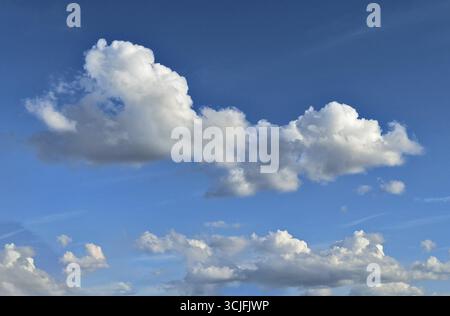 White altocumulus clouds below in the background many cumulus clouds in front of a bright blue sky, international Stock Photo