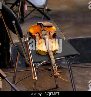 Image of an old violin and bow lying on a chair in a theater Stock Photo