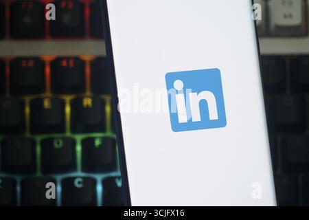 Screen displaying LinkedIn app icon on smartphone with colorful keyboard backdrop Stock Photo