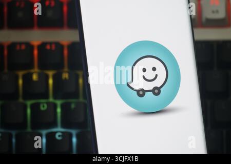 Waze icon on smartphone screen, depicting navigation, with a keyboard background Stock Photo