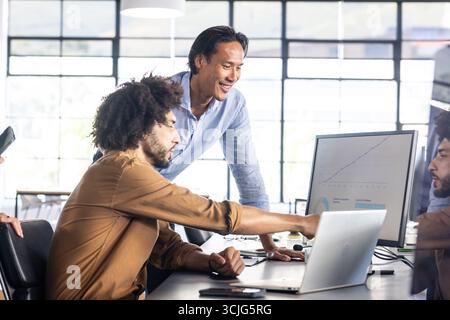 Analyzing data on computer screen, colleagues collaborating on project in office Stock Photo