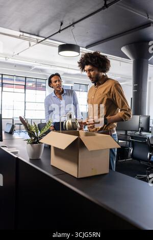 Colleagues unpacking box in modern office, discussing new project ideas Stock Photo