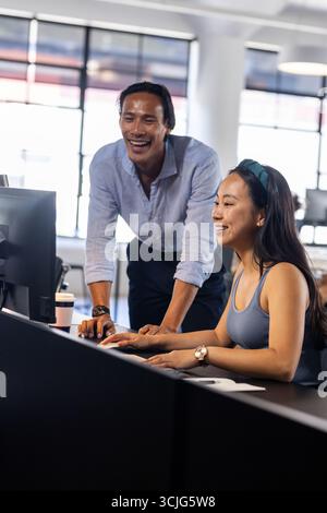 Colleagues collaborating on computer in modern office, sharing ideas and solutions Stock Photo