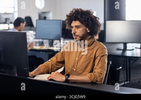 Focused African American man working on computer in modern office environment Stock Photo
