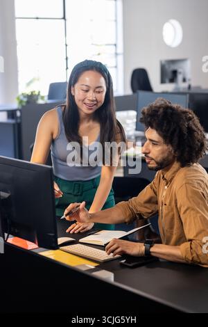 Colleagues collaborating at office desk, discussing project on computer screen Stock Photo
