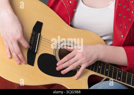 Cropped close-up view of guitar body and hands of female guitarist in relaxed position during break in performance Stock Photo