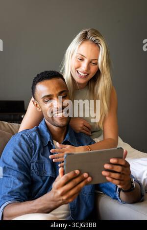Happy couple using tablet at home, smiling and enjoying time together Stock Photo