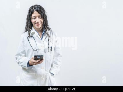 Smiling female doctor using smart phone isolated. Doctor holding phone, Concept of online medical services Stock Photo