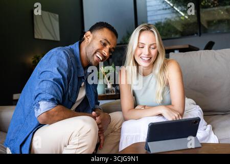 Smiling couple watching video on tablet together at home, enjoying leisure time Stock Photo