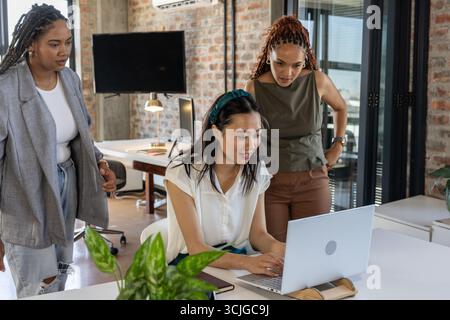 Collaborating in modern office, team discussing project details using laptop Stock Photo