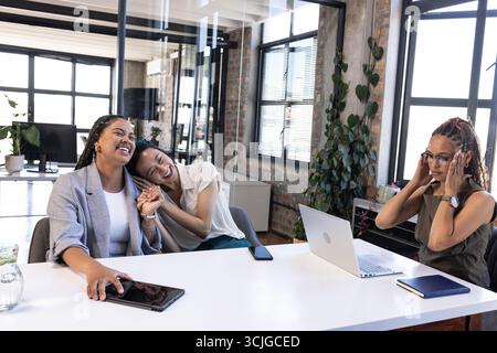 Colleagues celebrating success at office, smiling and using laptop and tablet Stock Photo