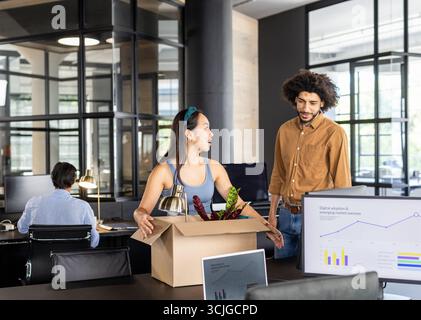 Colleagues in modern office discussing project with charts on computer screens Stock Photo