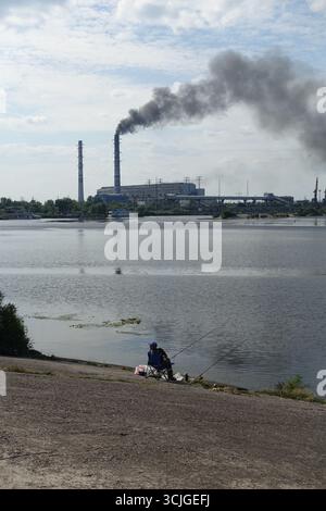 A man fishing near a power plant, in Ukraine, in a polluted area Stock Photo