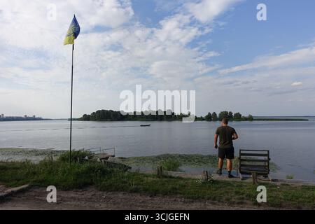A man and a Ukrainian flag near a lake in the Kyiv region Stock Photo