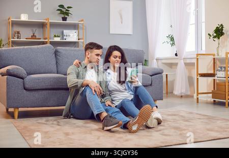 Family Couple Enjoying Leisure Time Together At Home And Using Phone Stock Photo