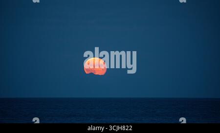 Super moon full moon rising above the sea with reflection, over Irish Sea Stock Photo