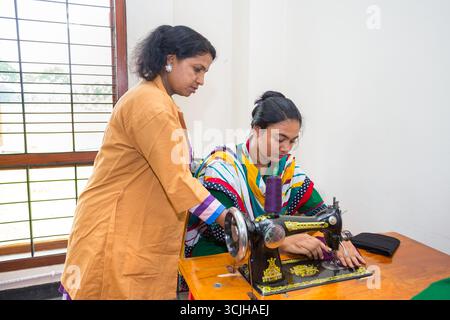 Bangladesh – May 21, 2019: A teacher teaches her students to sew clothes using a sewing machine in the Chuadanga district. Stock Photo