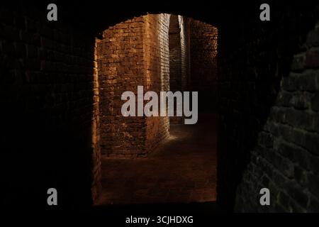 Dark underground brick passage in Kalemegdan Fortress, Belgrade, with dramatic lighting on old stone walls. Stock Photo