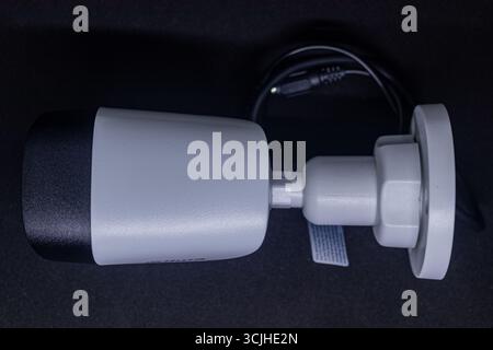 White CCTV Security Camera with Black Lens Housing on Black Studio Background. Stock Photo