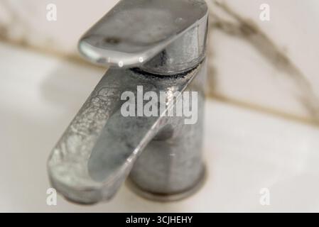 Dirty chrome tap faucet in the bathroom is covered plaque limescale due to hard water Stock Photo