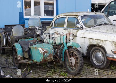 Wroclaw, Poland - August 28 2025: Abandoned Soviet motorcycles and GAZ Volga in industrial yard Stock Photo
