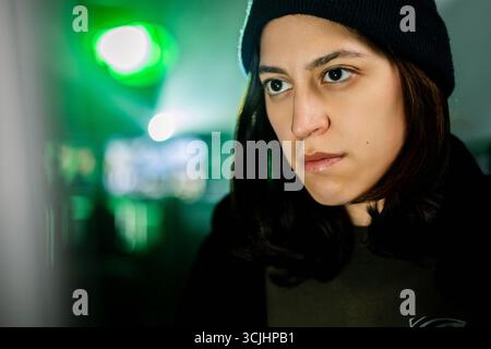 Female young hacker working on computer in dark room programming code Stock Photo