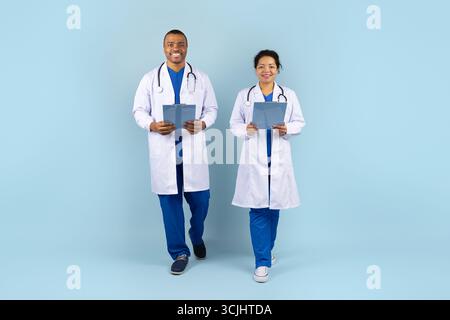 African American male and female doctors in lab coats walking with clipboards Stock Photo