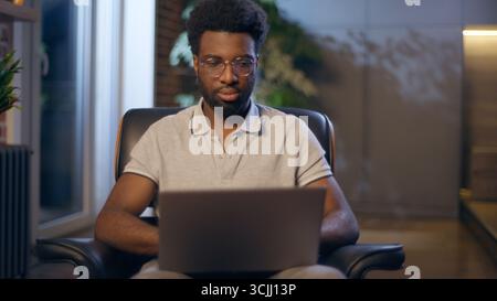 African American guy student business man in night office businessman entrepreneur thoughtful male worker overtime evening laptop online working Stock Photo