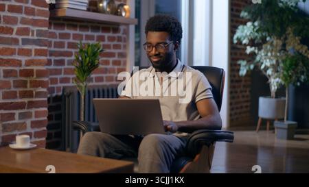 African American man businessman business employer typing laptop in night office overtime online studying deadline task in evening smiling guy male Stock Photo
