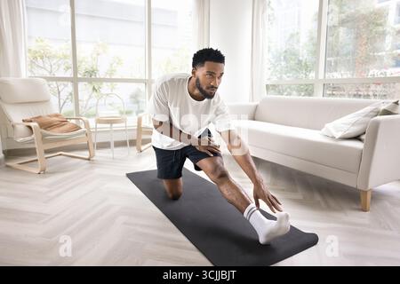 Young man practice stretching exercises on yoga mat at home Stock Photo