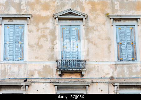 Closed shutters on the windows of a dilapidated building in the historic centre Stock Photo