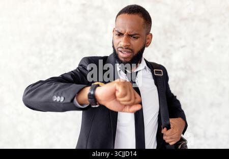Scared man is late for work looking at wrist watch Stock Photo