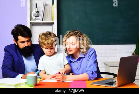 Private lesson. Primary school pupil having lesson with private tutors. Education, learning. Male and female teacher with schoolboy at desk in classro Stock Photo