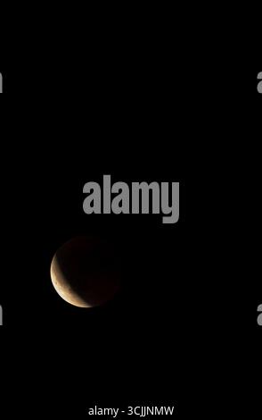 Earth's shadow covering part of the moon during a partial lunar eclipse Stock Photo