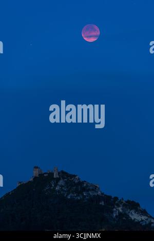 Scenic view of the pink full moon rising over the medieval castle ruins of Staatz in Lower Austria, Austria, during blue hour Stock Photo